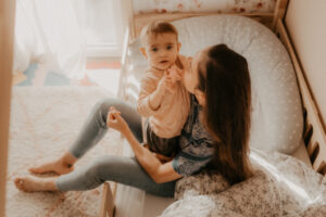 une jeune maman tient son bebe dans les bras dans chambre bebe