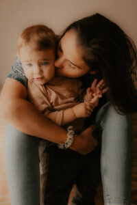 une jeune maman enlasse et fait un bisous a son bebe de un an