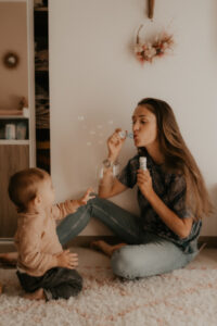une maman fait des bulles devant son bebe dans la chambre