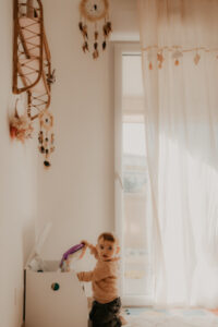 un bebe prend un livre dans le coffre a jouets de sa chambre