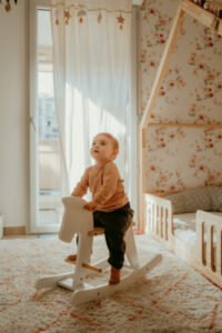 un bebe joue sur un cheval a bascule dans sa chambre