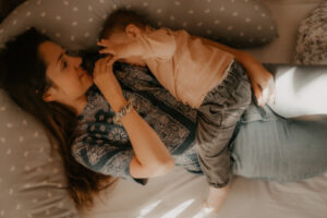 une jeune maman allaite son bebe allongee sur le lit