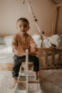 bebe fille joue sur un cheval a bascule dans sa chambre