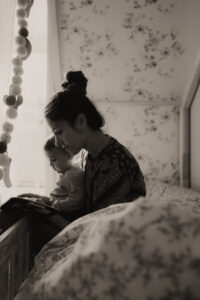 une maman lit un livre a son bebe assis sur ses genoux dans chambre