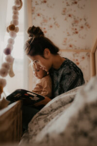 une maman lit un livre a son bebe a la maison sur le lit
