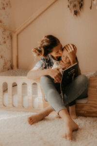 une maman embrasse son bebe en lui lisant une histoire sur le lit