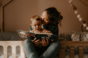 une jeune maman embrasse sa fille qui regarde un livre