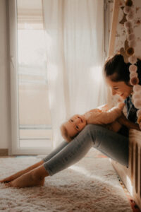 une maman chatouille son bebe allongee sur ses jambes