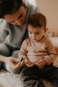une maman donne une figurine a son bebe dans la chambre