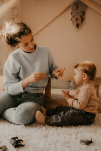 une maman et son bebe jouent aux figurines animaux a la maison
