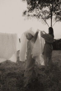une petite fille joue avec le linge que sa maman etend dans le jardin