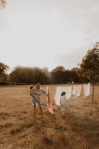 une maman etend le linge dans le jardin avec ses enfants