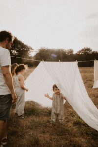 une famille construit une cabane avec des draps etendu dans le jardin