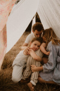 une famille fait un calin cache sous les draps etendus