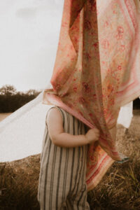 un petit garcon se cache dans un foulord louise misha etendu dans le jardin