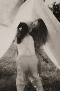 une maman et ses enfants se cache dans les draps qui sechent dans le jardin