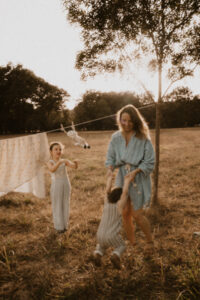 une maman et ses enfants jouent dans les champs au milieu des draps etendus