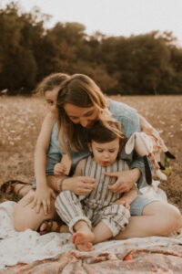 une maman entouree de ses deux enfants dans un champs de fleurs