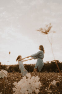 une maman et sa fille tournent en se tenant les mains dans champs de fleurs vaugrenier