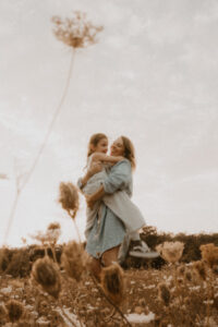 une maman porte sa fille dans un champs de fleurs dans les alpes-maritimes