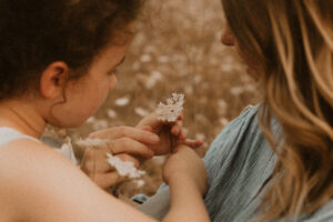 une maman et sa fille cueille une fleur de champs