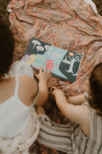 deux enfants lisent un livre dans herbe
