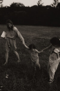 une maman et ses enfants se tiennent la main en marchant dans un champs