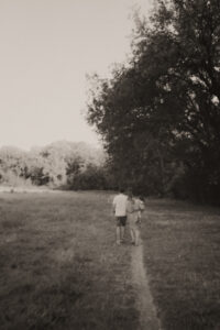 un couple se tient par le bras bebe dans les bras en marchant au parc