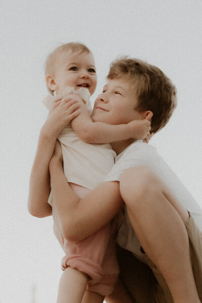un petit garcon serre sa petite soeur dans les bras lors de leur seance photo famille