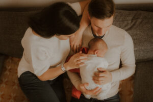 de jeunes parents prennent le temps de caliner leur nouveau-ne pendant leur seance photo a domicile