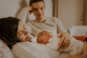 pendant le shooting naissance la photographe prend des photos de leur quotidien de bebe endormi sur maman allongee sur le lit