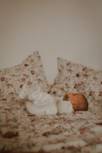 photo bebe allonge sur le lit pendant la seance photo naissance