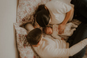 bebe dort entre ses parents sur le lit durant la seance photo naissance