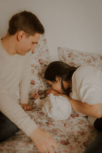 les parents prennent le temps de faire des bisous a leur nouveau-ne pendant la seance photo lifestyle a la maison