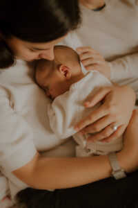 une maman prend le temps de caliner son bebe endormi contre elle pendant la seance photo naissance du nouveau-ne a domicile a nice