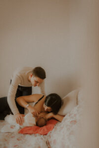 pendant la seance photo naissance la maman allaite son bebe allonges sur le lit