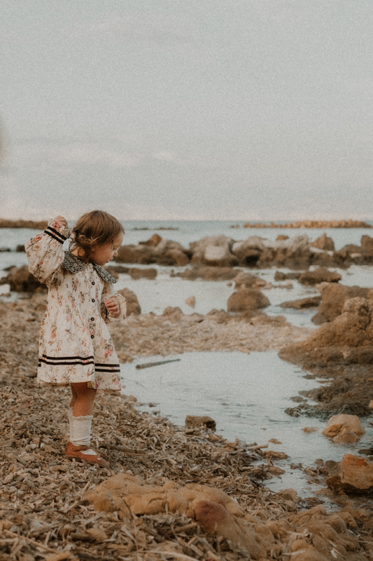 une petite fille jette des cailloux a la mer pendant la seance photo avec photographe famille antibes