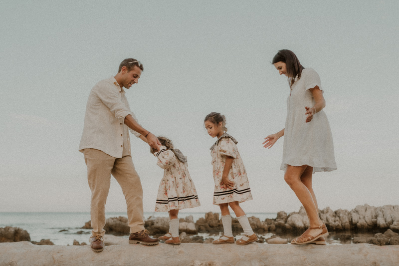 une famille marche en se tenant les mains sur la plage cap antibes pour des photos naturelles