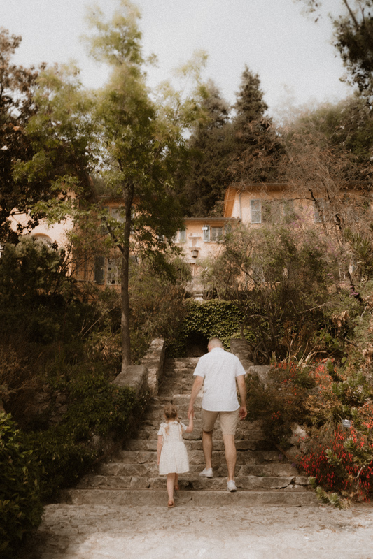 en seance photo lifestyle un papa marche en donnant la main a sa petite fille dans les jardins des alpes-maritimes