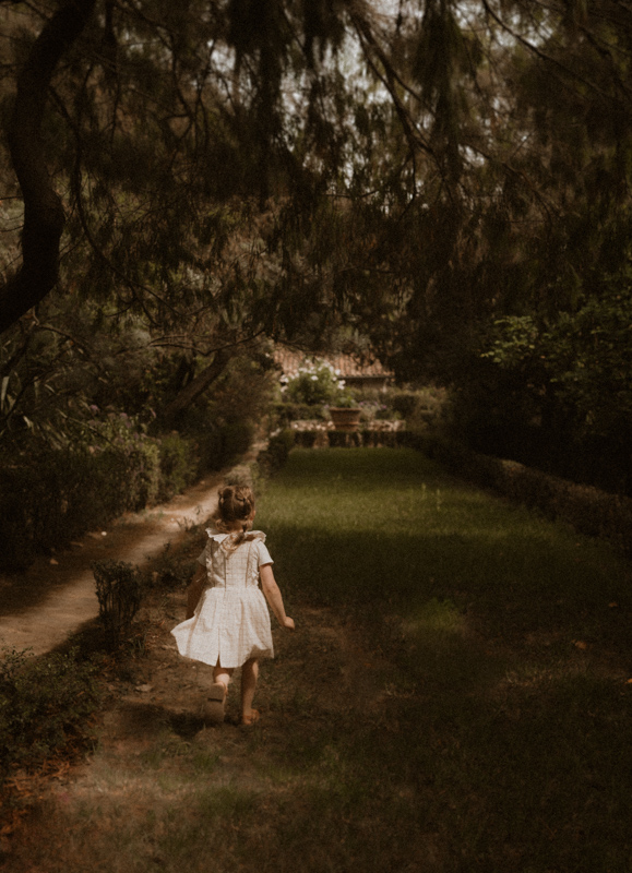 une petite fille court dans les jardins pendant seance photo en exterieur dans les alpes-maritimes