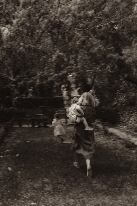 une maman court dans le jardin avec ses enfants dans les alpes-maritimes pour des photos de famille naturelles