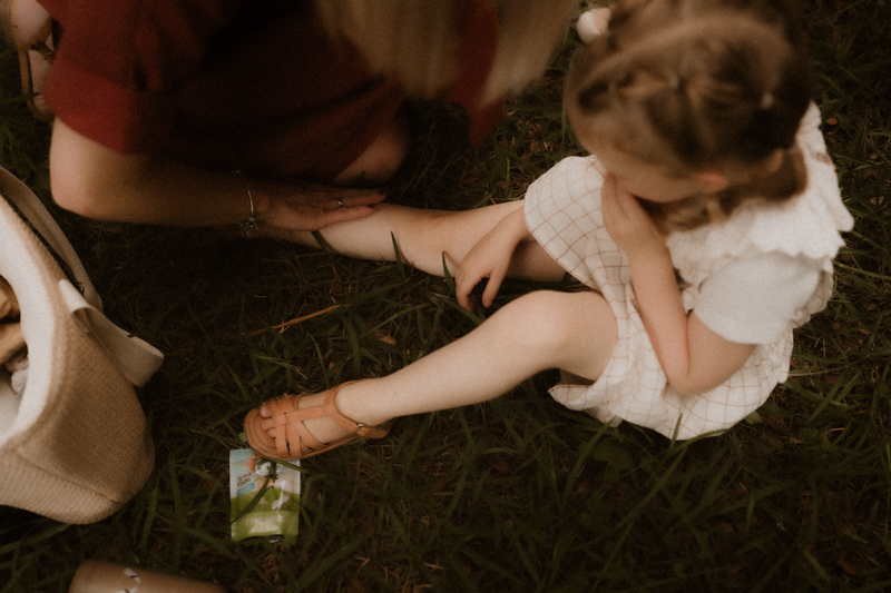 une maman soigne un bobo sur la jambe pendant seance photo famille