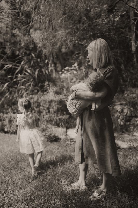 une maman allaite son bebe et sa fille joue dans le jardin pendant seance photo famille