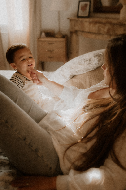 maman et bebe jouent sur le lit en seance photo maternite a domicile