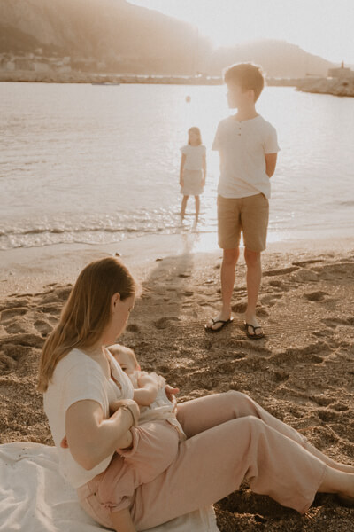 une maman allaite son bebe pendant leur seance photo famille sur la plage des sablettes a menton 