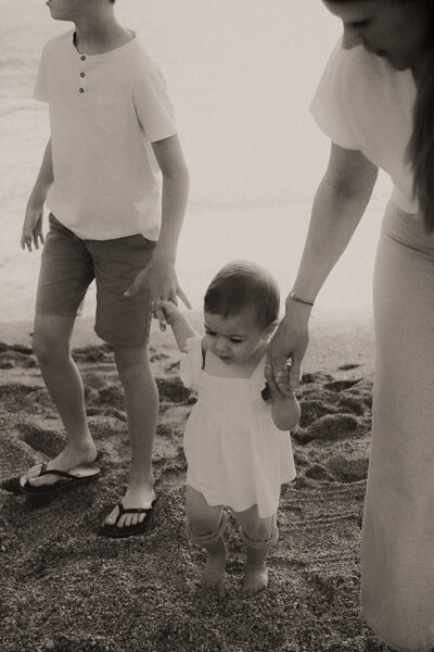 un bebe fait ses premiers pas sur la plage des sablettes a menton en tenant la main de son frere et sa maman