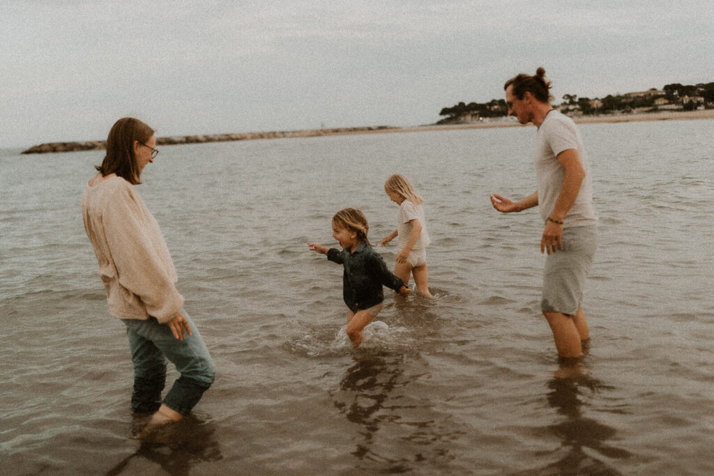 une famille joue a la mer au coucher du soleil